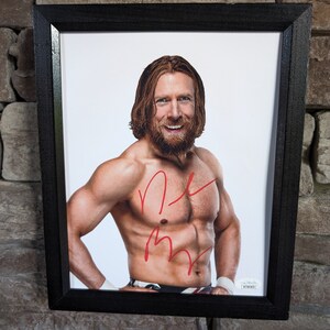 Könnte beinhalten: Ein gerahmtes Foto eines Mannes mit langen roten Haaren und Bart. Er ist oben ohne und hat einen muskulösen Körperbau. Das Foto ist mit roter Tinte signiert. Die Unterschrift lautet "R.M."