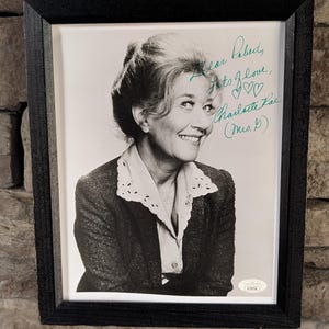 May include: Black framed portrait of Charlotte Rae, a smiling woman in a blazer and blouse. The portrait is signed in green ink with the words "Dear Robert, Lots of Love, Charlotte Rae (Mrs. P)".