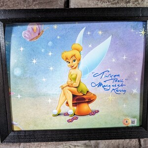 May include: Framed print of Tinker Bell sitting on a mushroom with a blue, green, and yellow background. The print is signed "Tinker Bell" and "Mary Kerry".