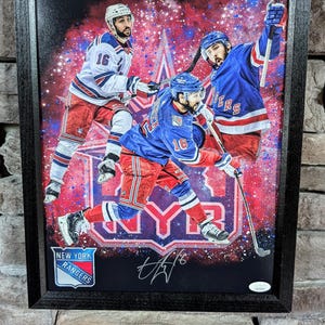 May include: Framed canvas print of three hockey players wearing blue and red jerseys with the New York Rangers logo. The players are in a dynamic pose with a red, white, and blue background. The print is signed with a black signature.