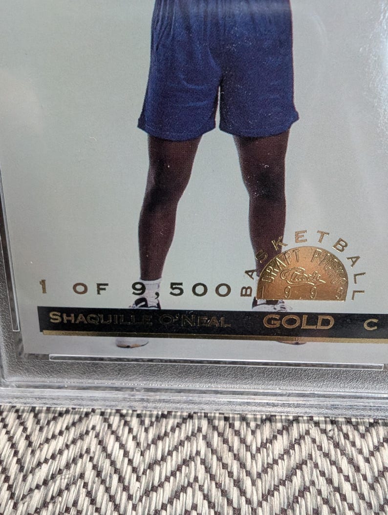 May include: Shaquille O'Neal basketball card. The card is gold and encased in a protective holder. The card is numbered 1 of 9,500. The card has a gold seal that says "Basketball" and "Classics".