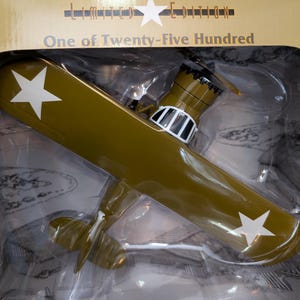 May include: A limited edition, olive green model airplane with white stars on the wings. The box reads "Limited Edition" and "One of Twenty-Five Hundred".
