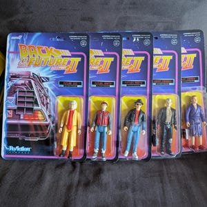 May include: Five action figures from the movie "Back to the Future Part II" in their original packaging. The figures include Future Doc, Future Marty, Fifties Marty, Griff Tannen, and Biff Tannen. Each figure is in a clear plastic bubble.