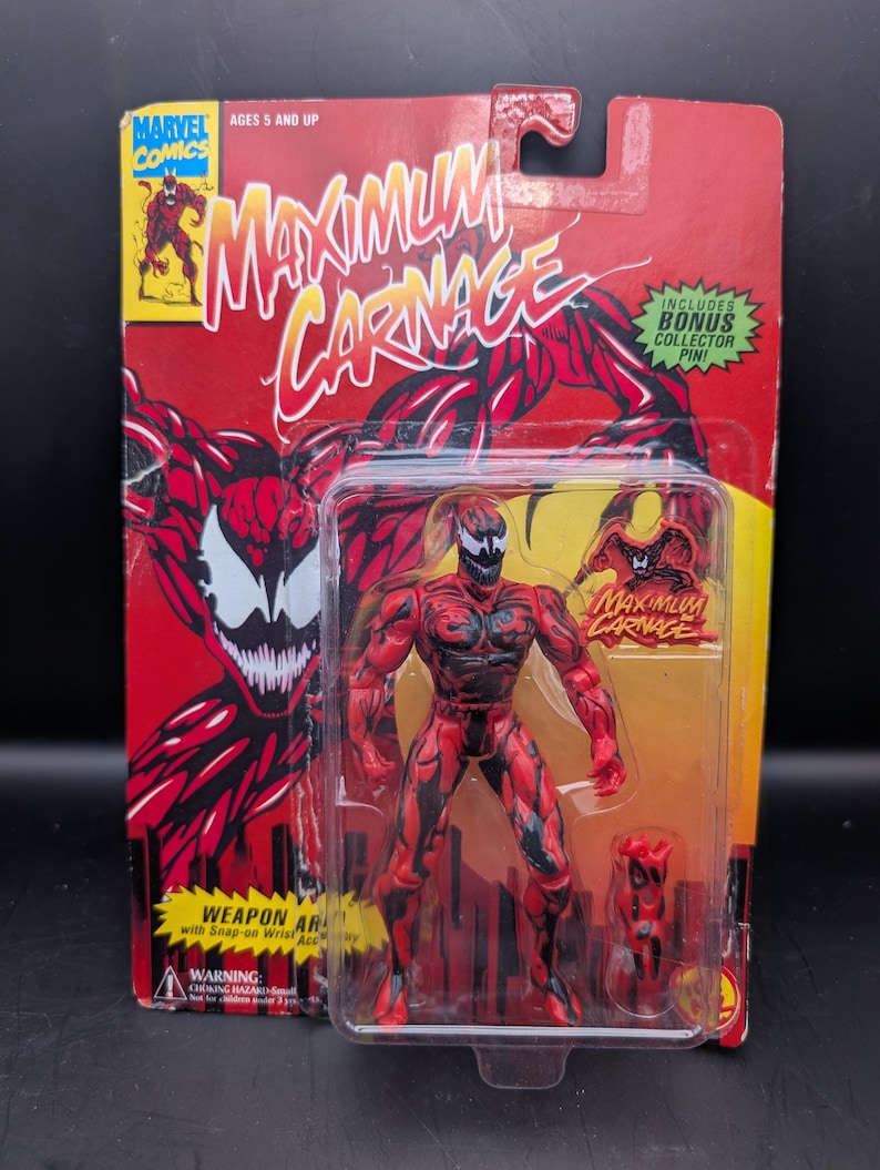 May include: A Maximum Carnage action figure in its original packaging. The figure is red with black accents and comes with a weapon accessory. The packaging is red and yellow with the Marvel Comics logo and the words "Maximum Carnage".