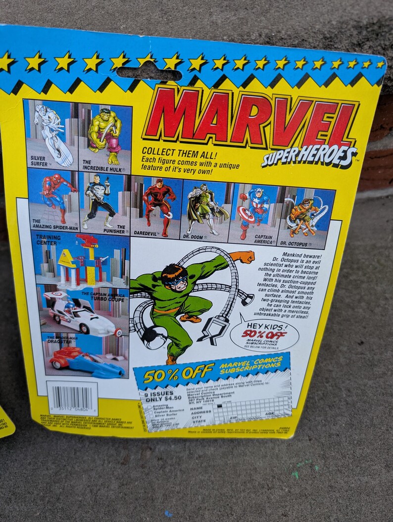 May include: A vintage Marvel Super Heroes action figure package. The packaging features illustrations of Silver Surfer, Hulk, Spider-Man, Punisher, Daredevil, Dr. Doom, Captain America, and Dr. Octopus. The package has a blue and yellow design with the Marvel logo.