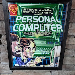 Puede incluir: Impresión enmarcada con Steve Jobs y Steve Wozniak con el texto "PERSONAL COMPUTER". La obra de arte tiene un estilo retro con una combinación de colores verde y azul. El marco es negro.