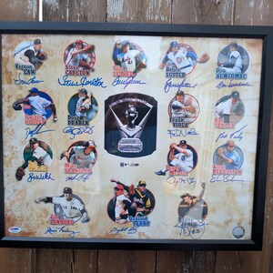 May include: Framed baseball memorabilia featuring multiple player signatures and a central trophy image. The signatures are arranged in circular frames against a sepia-toned background, all within a black frame. A collectible item for baseball fans.