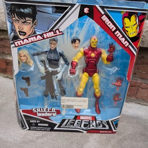 May include: A Marvel Legends action figure set featuring Iron Man and Maria Hill. The figures are posed in action stances and come with accessories. The packaging features the Marvel Legends logo and the characters' names.