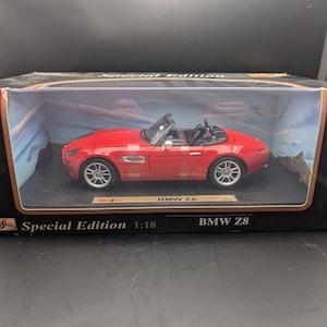 Op de afbeelding: Een rode BMW Z8 cabriolet modelauto in een zwarte doos. Het model is schaal 1:18, met zilveren wielen en zwart interieur. De doos leest "Special Edition" en "BMW Z8".