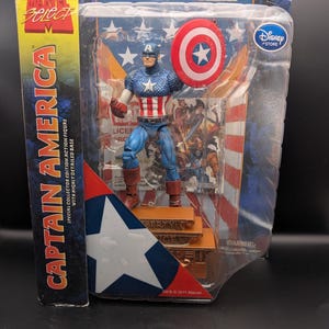 May include: A Captain America action figure in a clear plastic package. The figure is in a classic costume, holding a shield. The packaging includes the Marvel Select and Disney Store logos, with text that reads "Captain America".