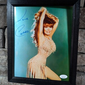 May include: A framed photograph of a woman with long red hair wearing a sequined dress. The woman is smiling and looking at the camera. The photograph is signed "Love,  [illegible]"