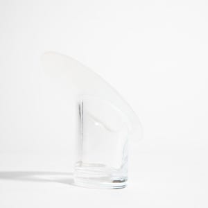 May include: A clear glass with a curved, frosted glass accent. The glass has a cylindrical shape with a rounded base. The frosted accent extends from the top, creating a unique, modern design. The glass is set against a white background.