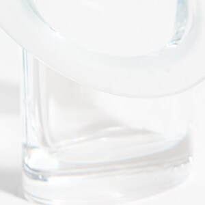 May include: A clear glass container with a rounded top and a square base. The glass is transparent, allowing light to pass through. The design is minimalist and modern, suitable for various uses.