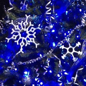 May include: A Christmas tree decorated with blue lights, white snowflakes, and silver ornaments.