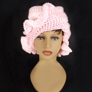 a crocheted hat with a ruffle on a mannequin head