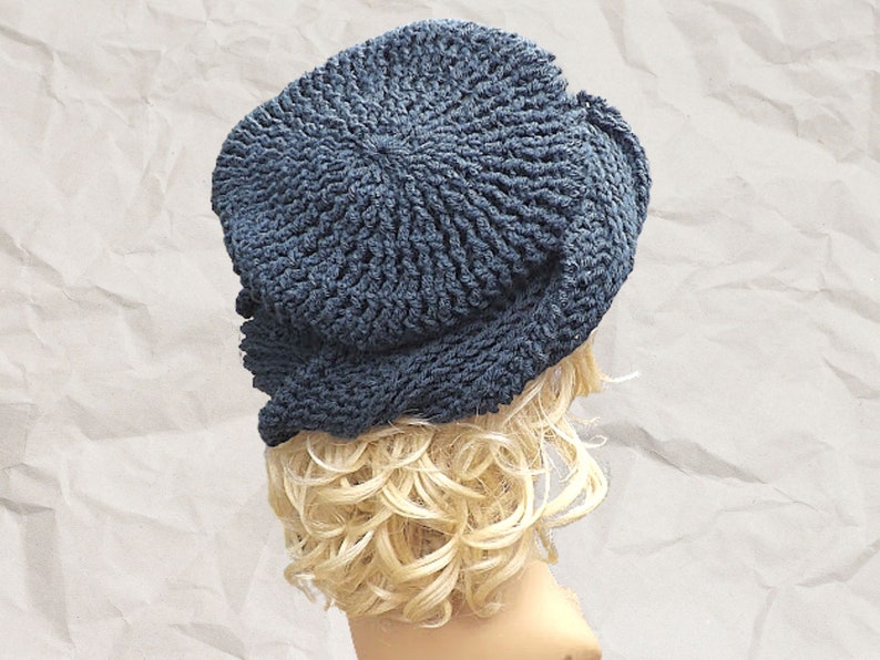 Back angle view of a mannequin head wearing a stylish navy Crochet Mobius hat with a distinctive Samantha slouchy design, set against a textured paper backdrop