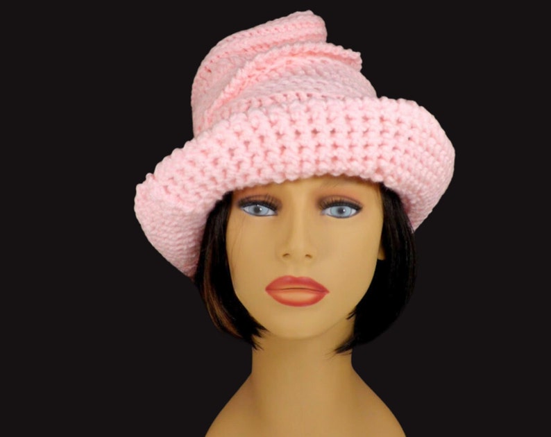 Angled front view of a pink Virginia Mobius strip crocheted cloche hat pattern on a mannequin, showcasing the unique twist and versatile design
