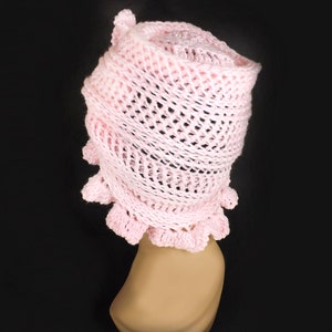 a crocheted hat with a ruffle on a mannequin head