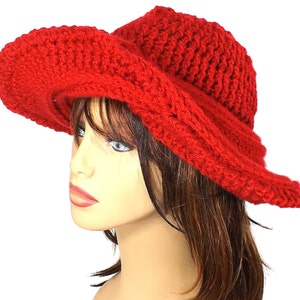 Elegant side view of the red Mobius crochet hat, showcasing the unique twist of the brim and the hat's sleek contours