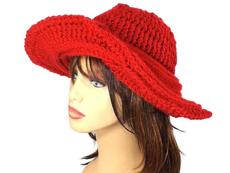 Elegant side view of the red Mobius crochet hat, showcasing the unique twist of the brim and the hat's sleek contours