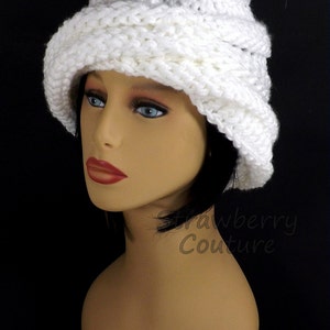 Close-up side view of a white Ombretta chemo cloche hat on a mannequin, emphasizing the intricate knitting pattern and the elegant Mobius design