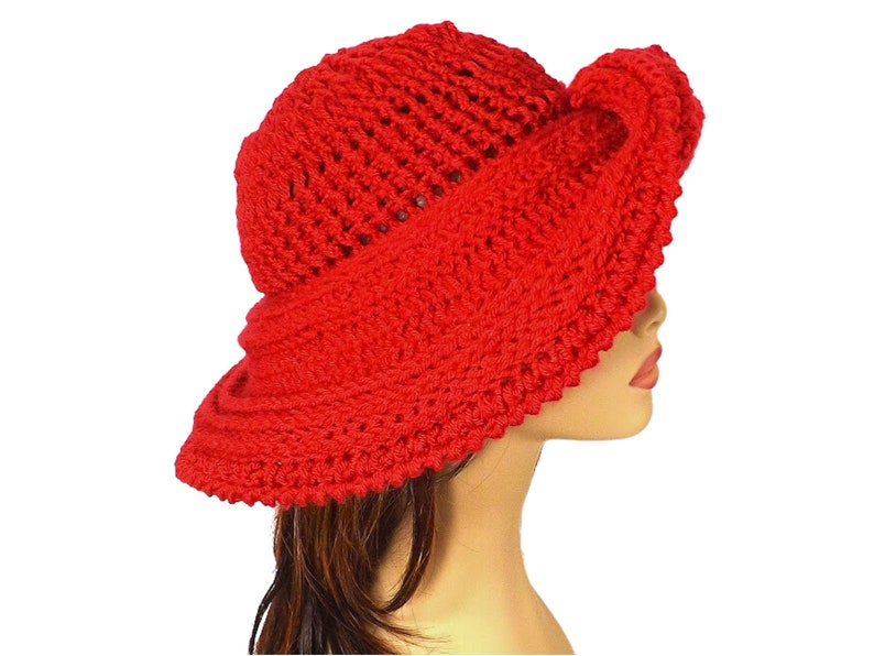 Red Mobius crochet hat with an intricate design, displaying the hat's profile with a twisted brim and full coverage on the mannequin's head