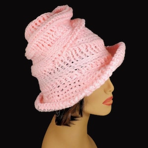 Side view of a soft pink Virginia Mobius strip crocheted cloche hat pattern on a mannequin, highlighting the elegant twist on top of the hat and textured design suitable for women and cancer patients.