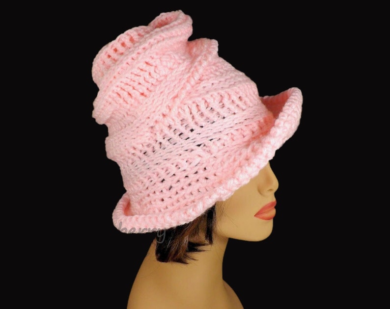 Side view of a soft pink Virginia Mobius strip crocheted cloche hat pattern on a mannequin, highlighting the elegant twist on top of the hat and textured design suitable for women and cancer patients.