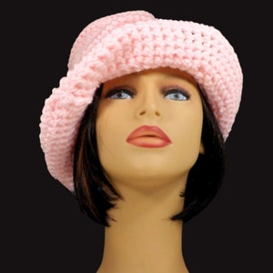 Front view of a mannequin head wearing a pink Virginia Mobius crochet cloche hat pattern, featuring a prominent brim and a stylish, slouchy fit