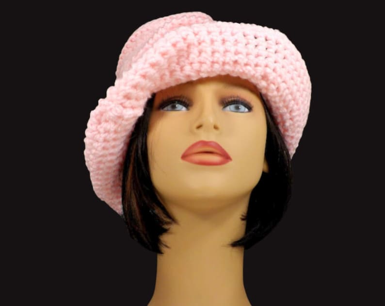 Front view of a mannequin head wearing a pink Virginia Mobius crochet cloche hat pattern, featuring a prominent brim and a stylish, slouchy fit