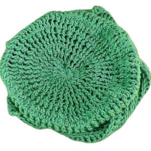 Unique Möbius Crochet Hat Pattern - Samantha Slouchy Beanie with Twist Brim. Top-down view of a handmade green crochet hat with a swirled, twisted pattern resembling a mobius strip. The hat has a slouchy, oversized fit.