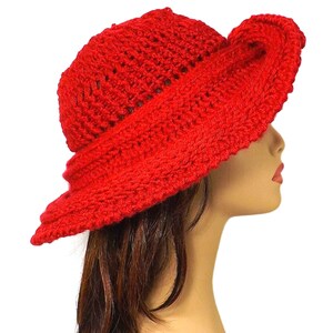 The red Mobius crochet hat worn with the brim styled down to partially cover the mannequin's face, showing off the hat's depth and texture