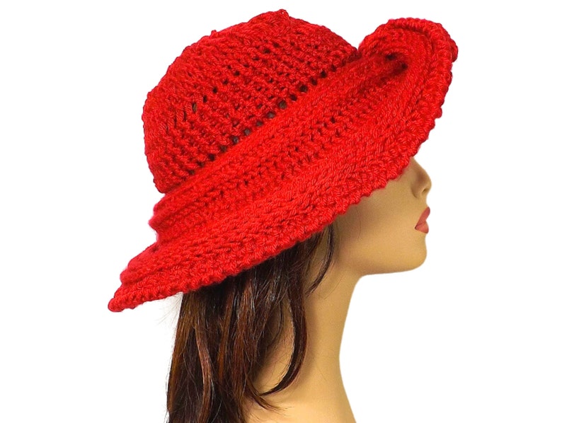 The red Mobius crochet hat worn with the brim styled down to partially cover the mannequin's face, showing off the hat's depth and texture