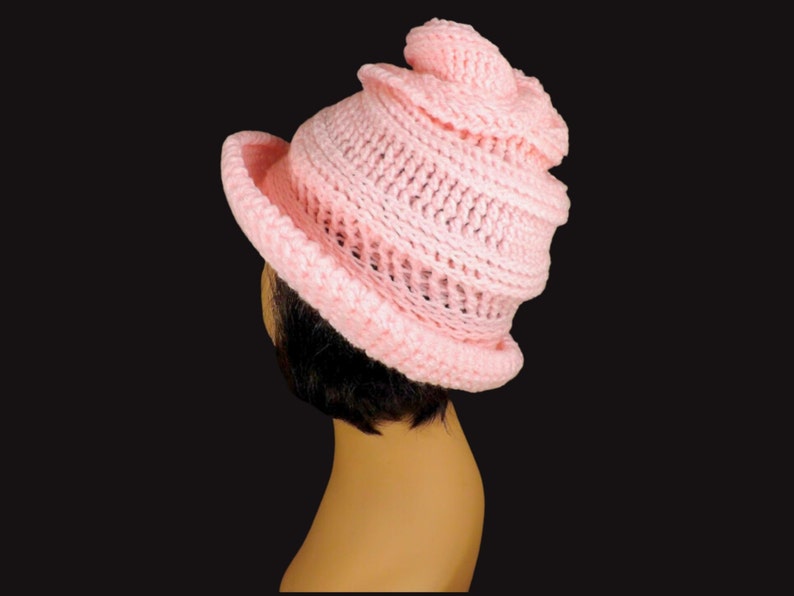 Top view of a mannequin head donning a pink Virginia Mobius strip crocheted cloche hat pattern, emphasizing the twisted pattern and snug fit