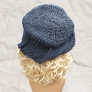 Three-quarter rear view of a navy blue Crochet Mobius hat featuring a Samantha slouchy fit and a twisted hatter brim, modeled on a mannequin with crumpled paper background