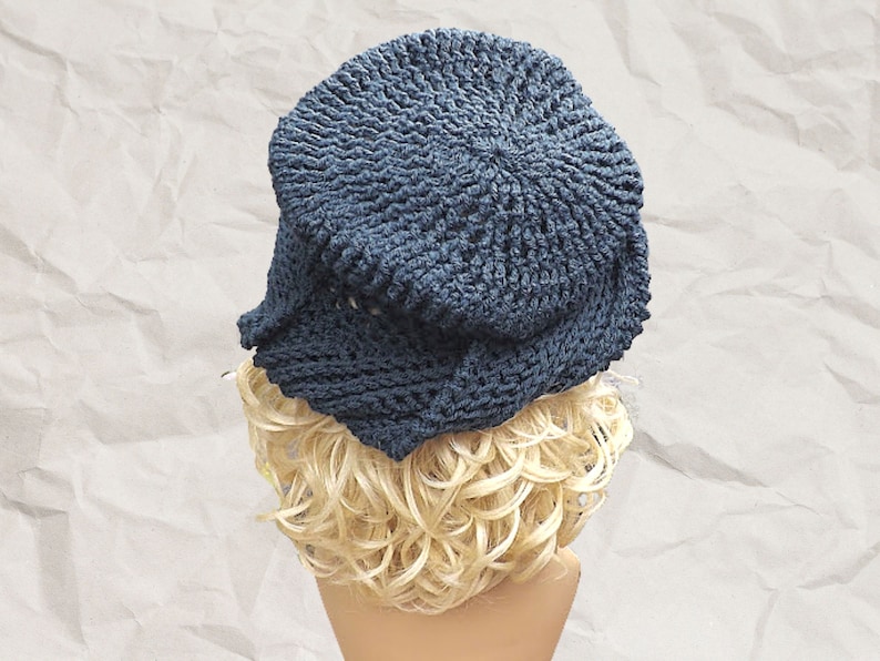Three-quarter rear view of a navy blue Crochet Mobius hat featuring a Samantha slouchy fit and a twisted hatter brim, modeled on a mannequin with crumpled paper background