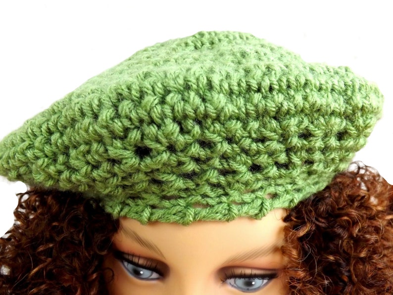 a close up of a mannequin head wearing a green crochet hat