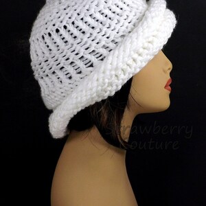 Side profile of a white knitted Ombretta chemo cloche hat on a mannequin, highlighting the hat's unique Mobius twist and textured pattern