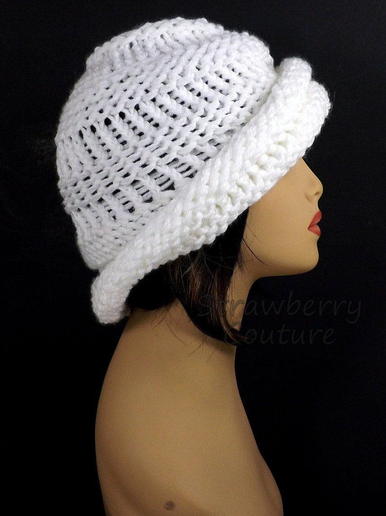 Side profile of a white knitted Ombretta chemo cloche hat on a mannequin, highlighting the hat's unique Mobius twist and textured pattern