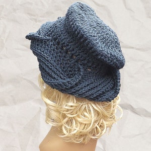 Mannequin head showcasing a slouchy navy blue Crochet Mobius hat pattern with a unique twisted brim, styled on crinkled paper background for a casual, artistic look