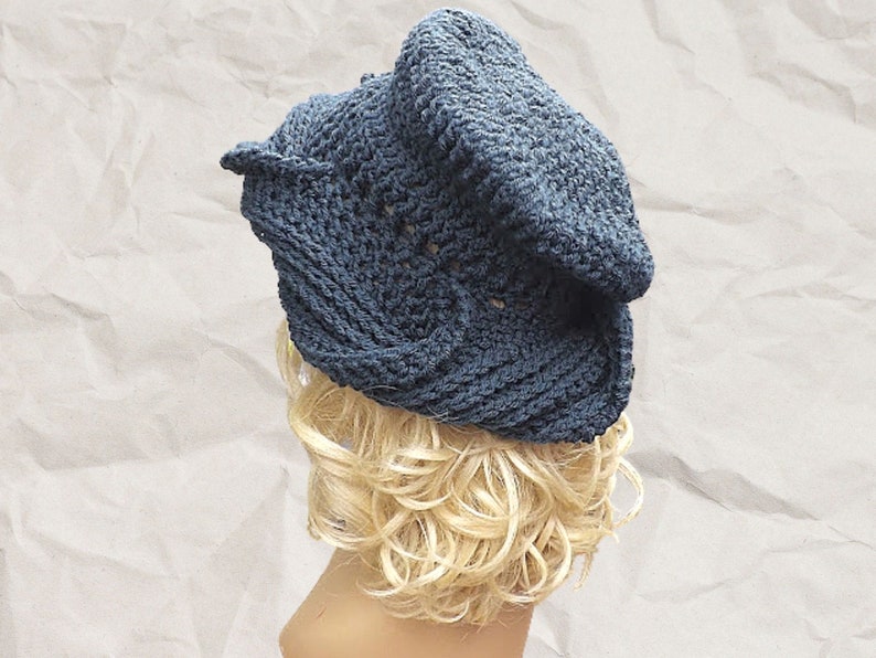 Mannequin head showcasing a slouchy navy blue Crochet Mobius hat pattern with a unique twisted brim, styled on crinkled paper background for a casual, artistic look