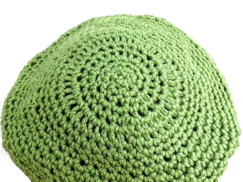 a green crocheted hat is shown on a white background