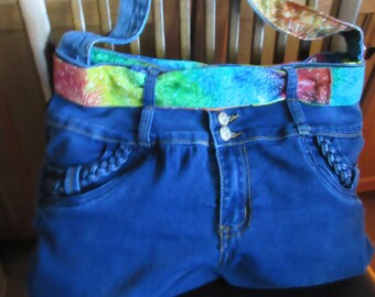May include: A blue denim tote bag with a rainbow fabric strap. The bag has a braided detail on the front pockets.