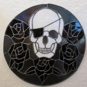 May include: A stained glass window featuring a white skull with an eye patch, surrounded by black roses.