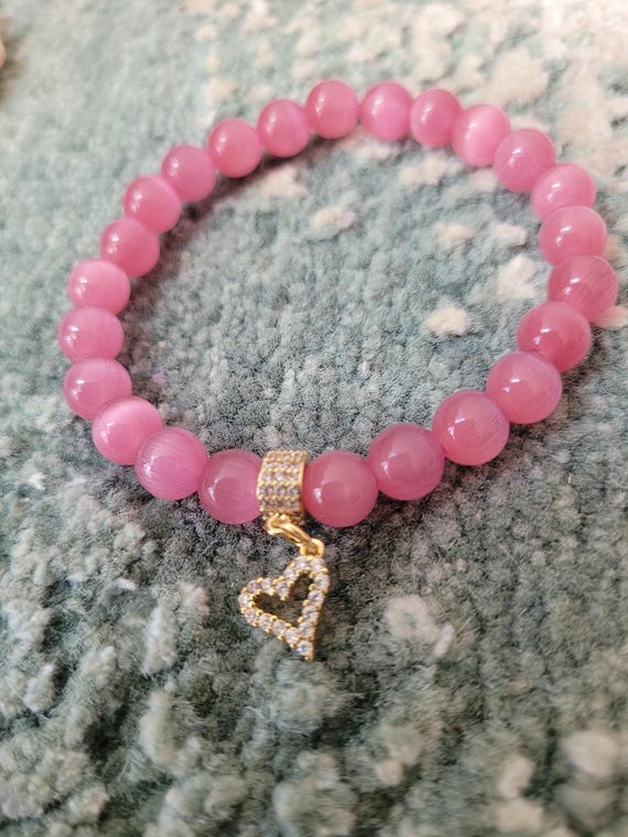 Energetically INSPIRING pink cats eye beads complimenting cz paved gold plated heart charm and bead stretch, stacking bracelet.