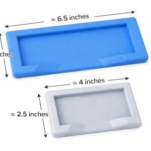 Puede incluir: Se muestran dos moldes rectangulares de silicona, uno azul y otro blanco. El molde azul mide aproximadamente 16,5 cm de largo y 6,4 cm de ancho. El molde blanco mide aproximadamente 10,2 cm de largo y 6,4 cm de ancho. Ambos tienen un borde elevado.