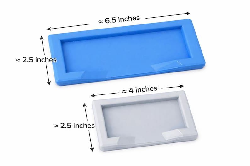 Puede incluir: Se muestran dos moldes rectangulares de silicona, uno azul y otro blanco. El molde azul mide aproximadamente 16,5 cm de largo y 6,4 cm de ancho. El molde blanco mide aproximadamente 10,2 cm de largo y 6,4 cm de ancho. Ambos tienen un borde elevado.