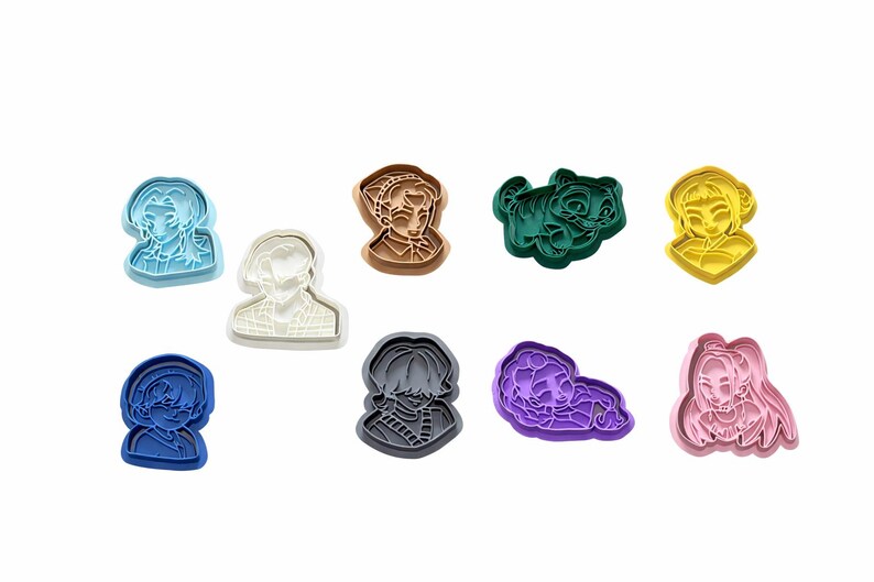 May include: A collection of nine plastic cookie cutters in various colors including light blue, white, brown, dark green, yellow, dark blue, gray, purple, and pink. Each cutter features a unique embossed character design with distinct facial features.