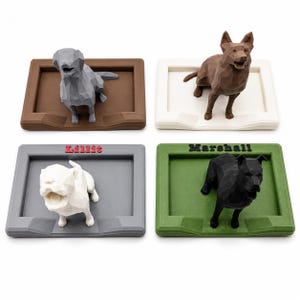 May include: Four low-poly dog figurines on rectangular bases. One gray dog on a brown base, one brown dog on a white base, one white dog on a gray base with the red text Lillit, and one black dog on a green base with the black text Marshall.