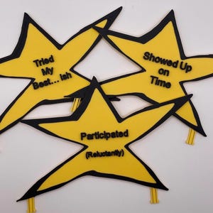 May include: Three yellow star-shaped decorations with black outlines and black text. The stars feature the phrases "Tried My Best... ish", "Showed Up on Time", and "Participated (Reluctantly)". Each star has a small yellow tab at the bottom.